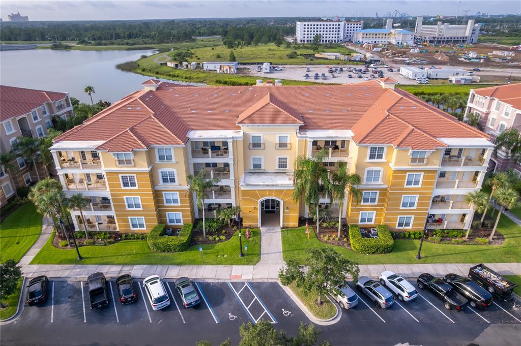 An aerial view shows a multi-story yellow apartment building with a tiled roof and parking — 5036 SHOREWAY LOOP UNIT 20705, ORLANDO, FL