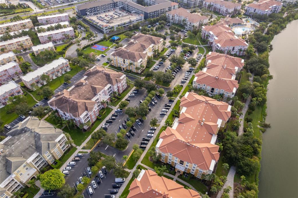 An aerial view shows multiple apartment buildings with orange roofs, parking lots, and a lake — 5036 SHOREWAY LOOP UNIT 20705, ORLANDO, FL
