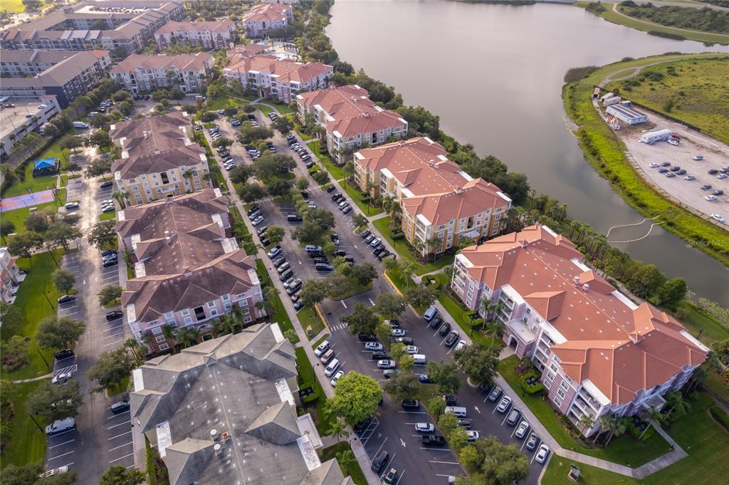 An aerial view shows several multi-story apartment buildings with red roofs near a lake — 5036 SHOREWAY LOOP UNIT 20705, ORLANDO, FL