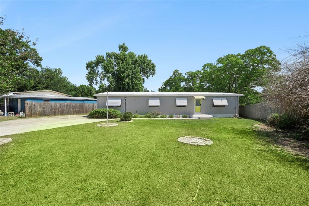 A single-story gray mobile home sits on a grassy lot with a concrete driveway — 16802 SUGAR BERRY LANE, MONTVERDE, FL