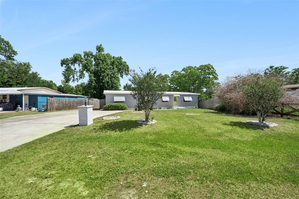 A single-story house with a light gray exterior sits behind a large, grassy front yard — 16802 SUGAR BERRY LANE, MONTVERDE, FL