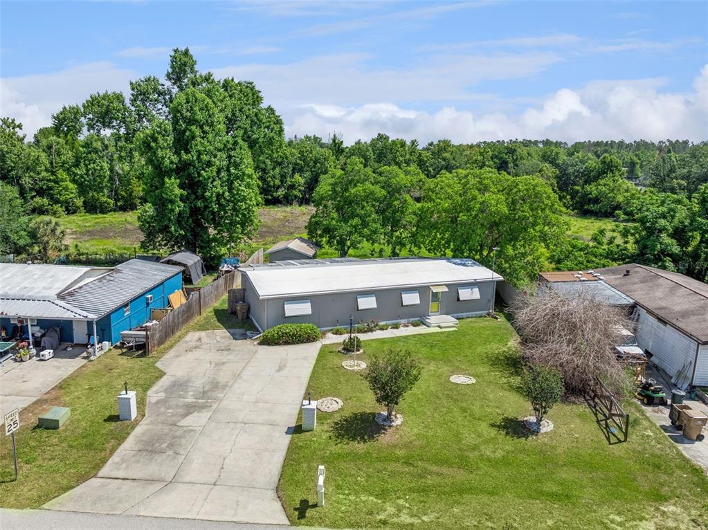 An aerial view shows a gray single-story house with a concrete driveway and surrounding trees — 16802 SUGAR BERRY LANE, MONTVERDE, FL