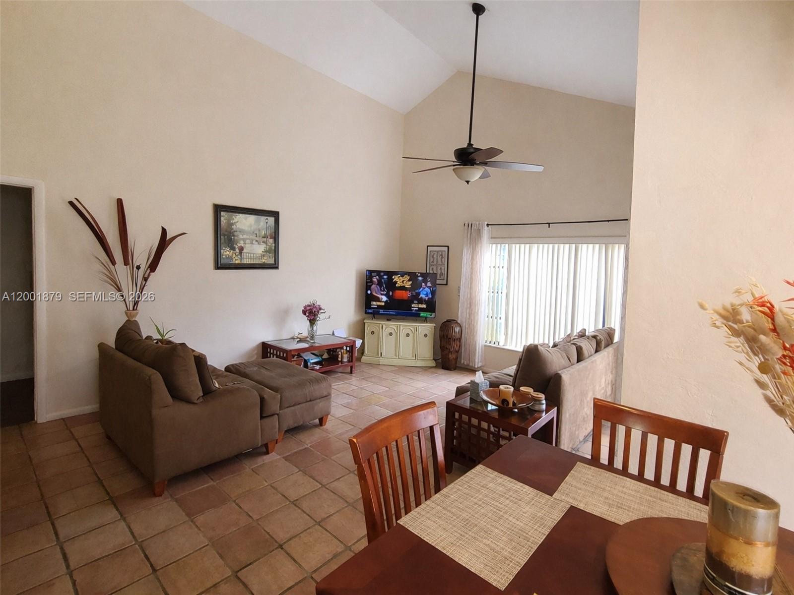 A living room with vaulted ceilings, tile floors, and a dining area in the foreground — 5524 Constant Spring Ter # 213, Lauderhill FL 33319, LAUDERHILL, FL