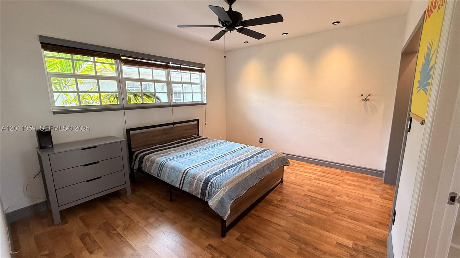 A bedroom features a bed, a gray dresser, wood flooring, and a ceiling fan — 8600 Byron Ave # 8, Miami Beach FL 33141, MIAMI BEACH, FL