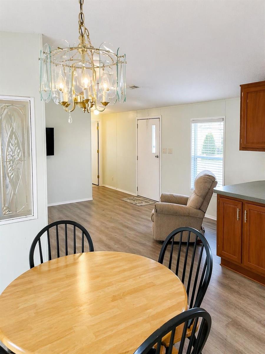 A dining area with a round wooden table and chandelier overlooks a living room space — 1905 SE 8th Avenue, Okeechobee FL 34974, OKEECHOBEE, FL