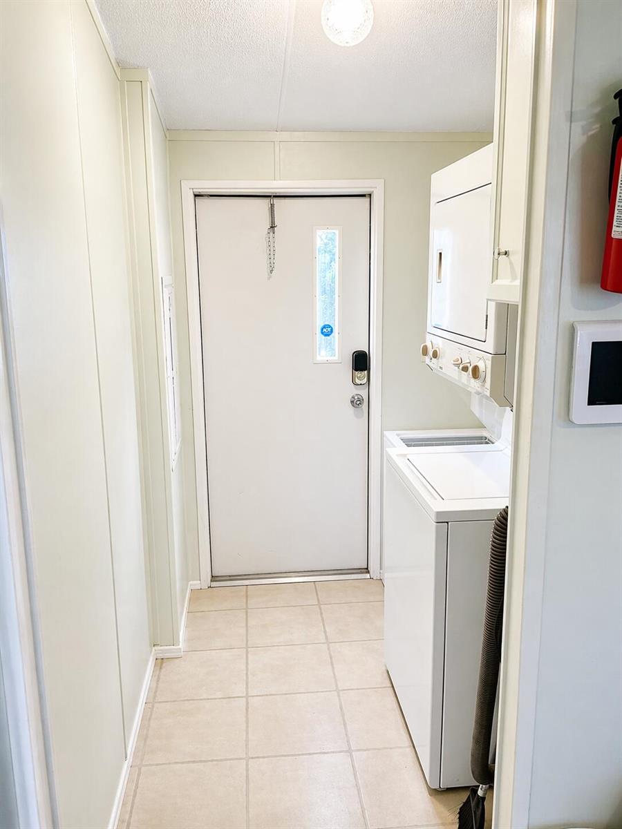 A laundry room features a stacked washer and dryer, tile flooring, and an exterior door — 1905 SE 8th Avenue, Okeechobee FL 34974, OKEECHOBEE, FL
