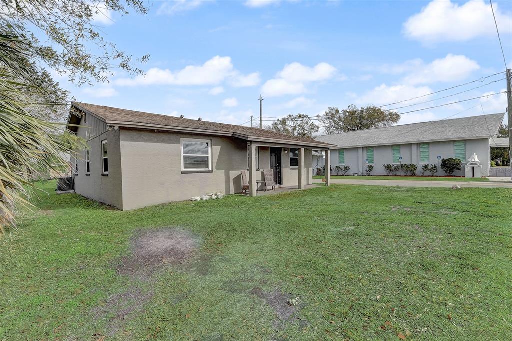 A single-story house with a covered porch sits on a grassy lot next to another building — 2590 E STATE ROAD 46, SANFORD, FL