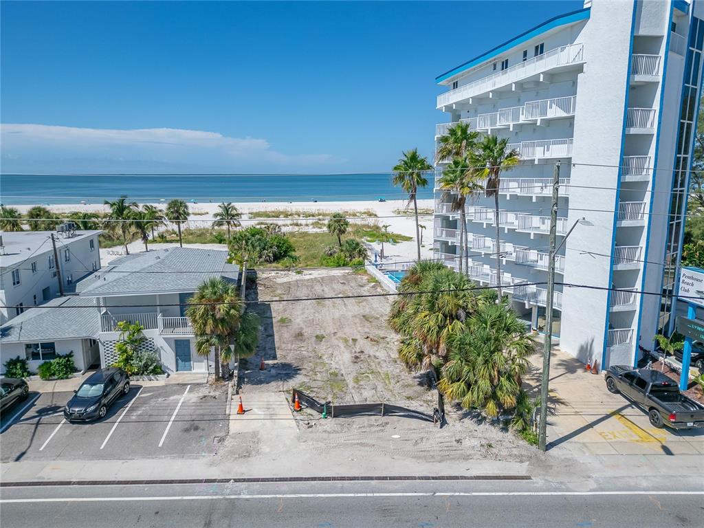 An aerial view shows a vacant lot situated between a residential building and a hotel — 10178 GULF BOULEVARD, TREASURE ISLAND, FL