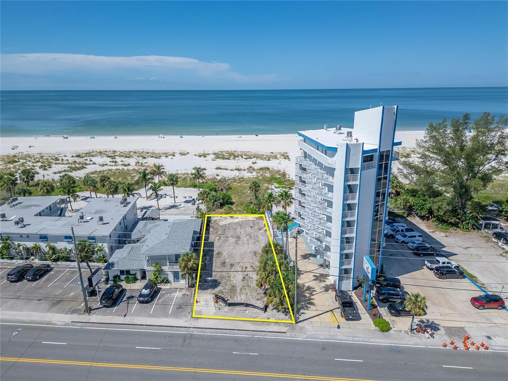 An aerial view shows a vacant rectangular lot situated between two buildings near the beach — 10178 GULF BOULEVARD, TREASURE ISLAND, FL