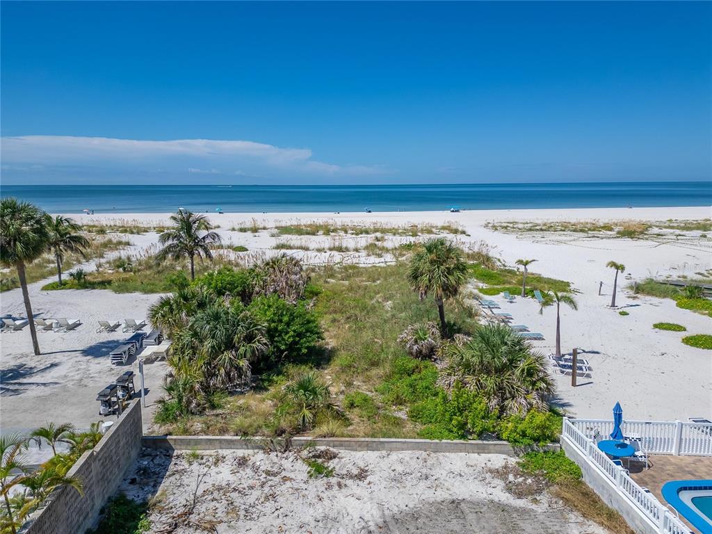 An elevated view of a sandy beach with palm trees and a private pool area — 10178 GULF BOULEVARD, TREASURE ISLAND, FL
