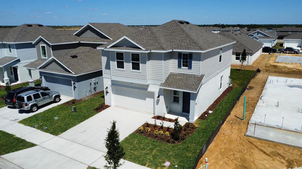 An aerial view shows a two-story suburban house with a white stucco base and siding — 441 SANDBAR LANE, HAINES CITY, FL