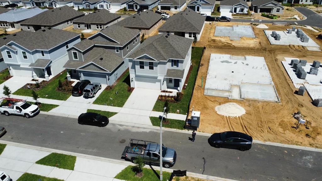 An aerial view shows several suburban houses and construction sites with concrete foundations — 441 SANDBAR LANE, HAINES CITY, FL
