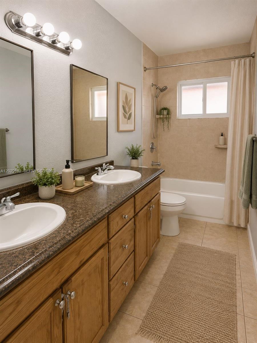 A bathroom features a double vanity with brown countertops, wooden cabinets, and a shower-tub combination — 701 SW 1st St # 1, Dania Beach FL 33004, DANIA BEACH, FL
