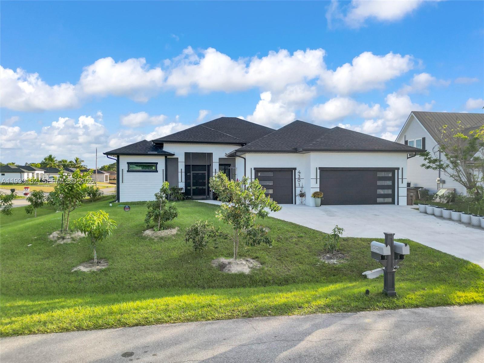 A modern single-story house with a white exterior, dark roof, and a three-car garage — 4301 10th ST W, Lehigh Acres FL 33971, LEHIGH ACRES, FL