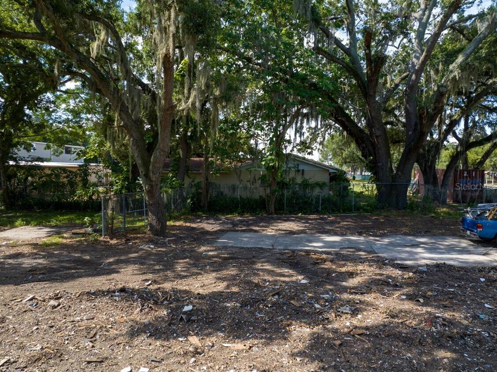 A dirt lot with a concrete pad sits in front of a fenced residential property — 6203 WINEGARD ROAD, ORLANDO, FL
