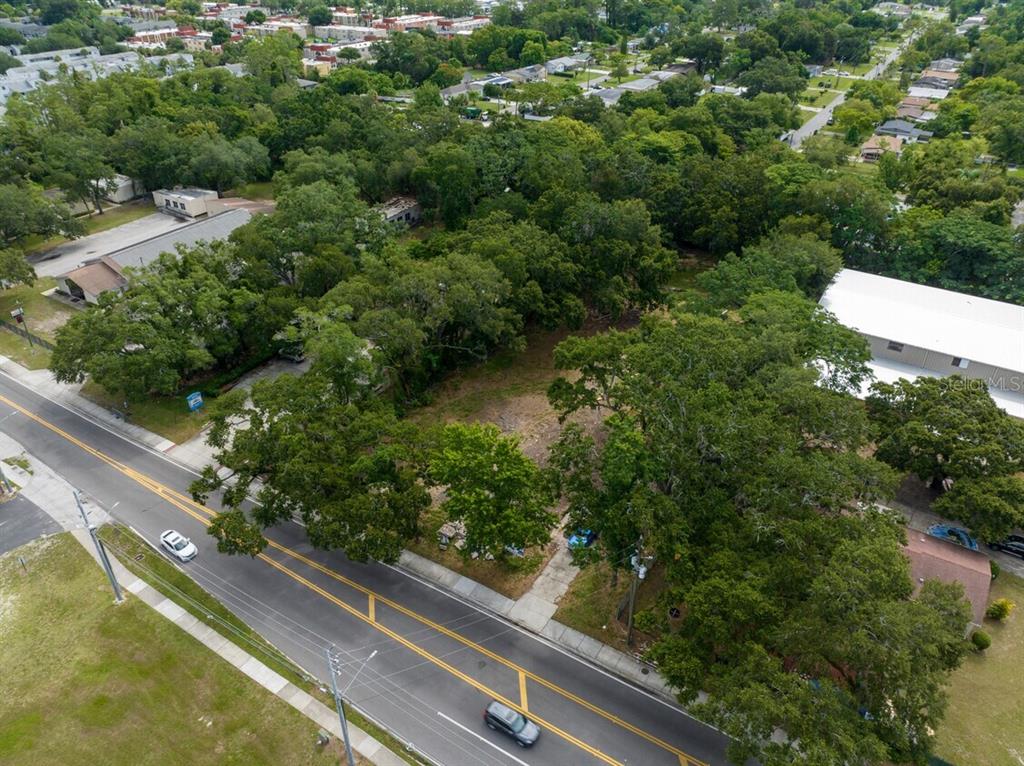 An aerial view shows a vacant, tree-covered lot situated between two commercial buildings along a road — 6203 WINEGARD ROAD, ORLANDO, FL