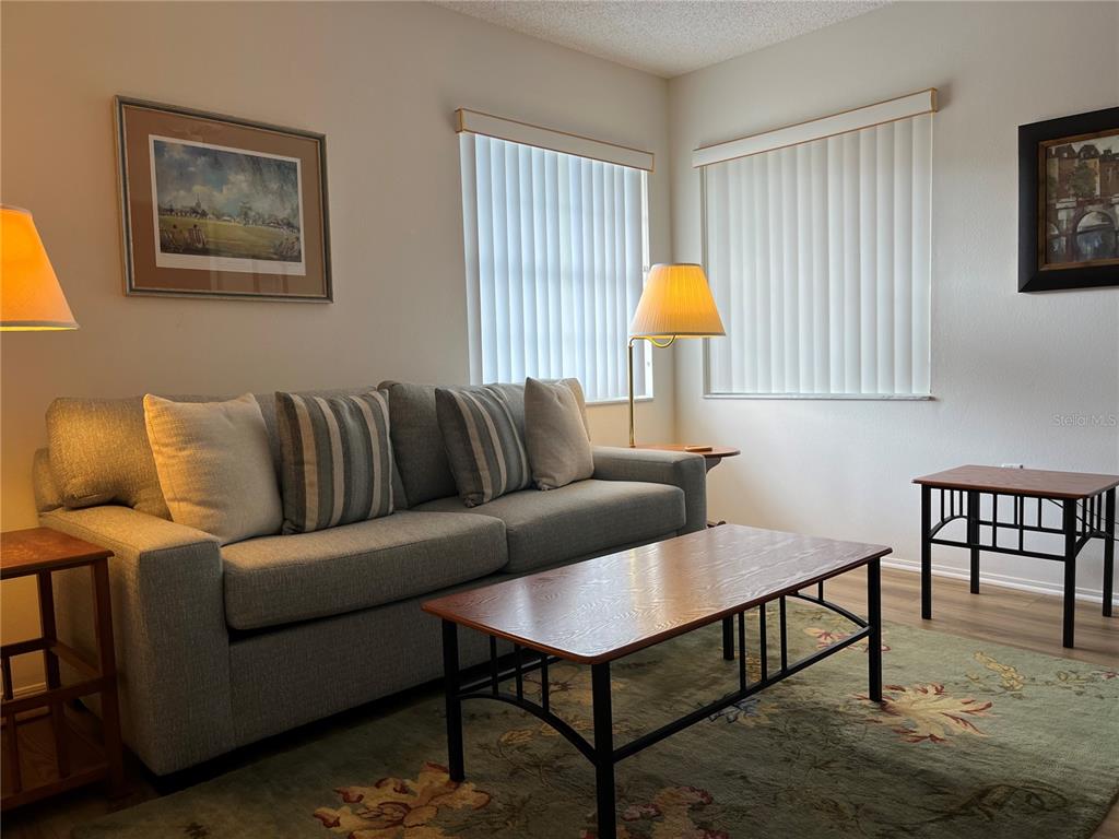 A living room features a grey sofa, a wooden coffee table, and two floor lamps — 1397 PERICO POINT CIRCLE UNIT 1397, BRADENTON, FL