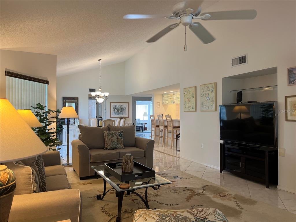 A living room with vaulted ceilings, tile floors, a ceiling fan, and an open kitchen — 1397 PERICO POINT CIRCLE UNIT 1397, BRADENTON, FL