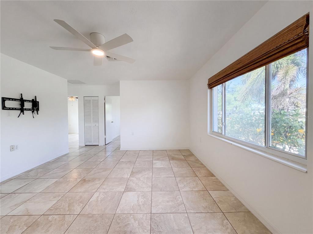A bright room features white walls, large beige floor tiles, and a ceiling fan — 829 E 4TH STREET, ENGLEWOOD, FL