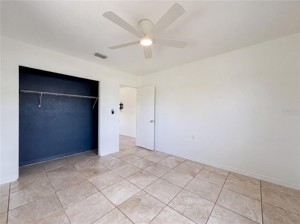 A bedroom features white walls, tile flooring, a ceiling fan, and a dark-painted closet — 829 E 4TH STREET, ENGLEWOOD, FL