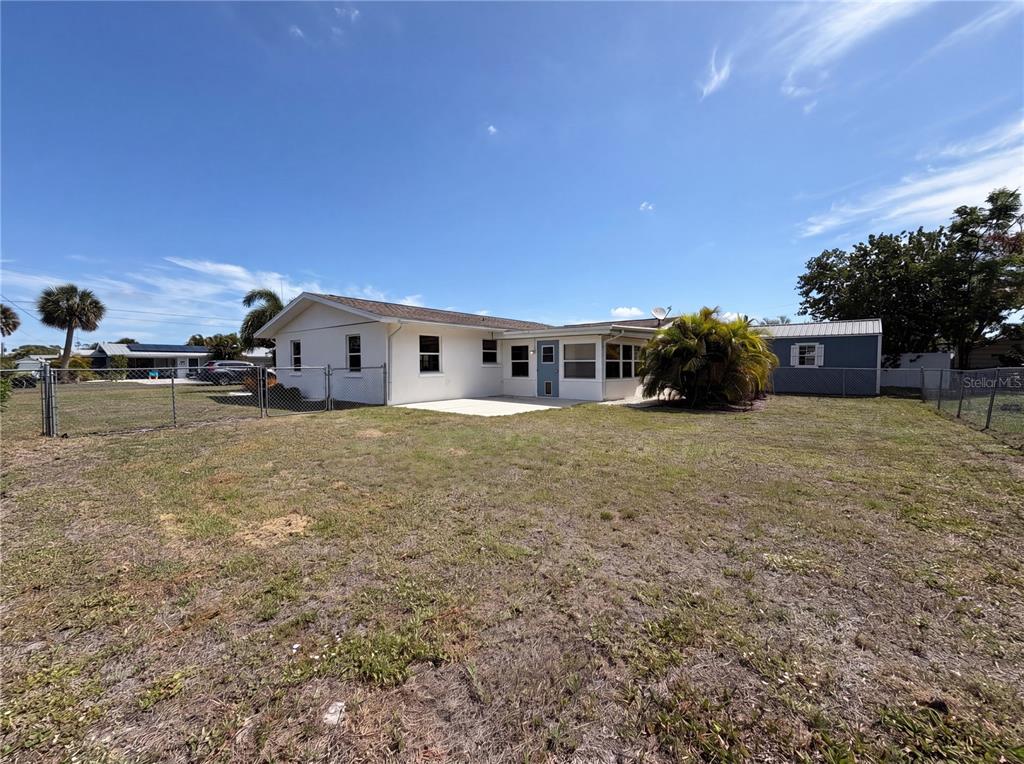 The backyard of a single-story house features a concrete patio, chain-link fencing, and a shed — 829 E 4TH STREET, ENGLEWOOD, FL