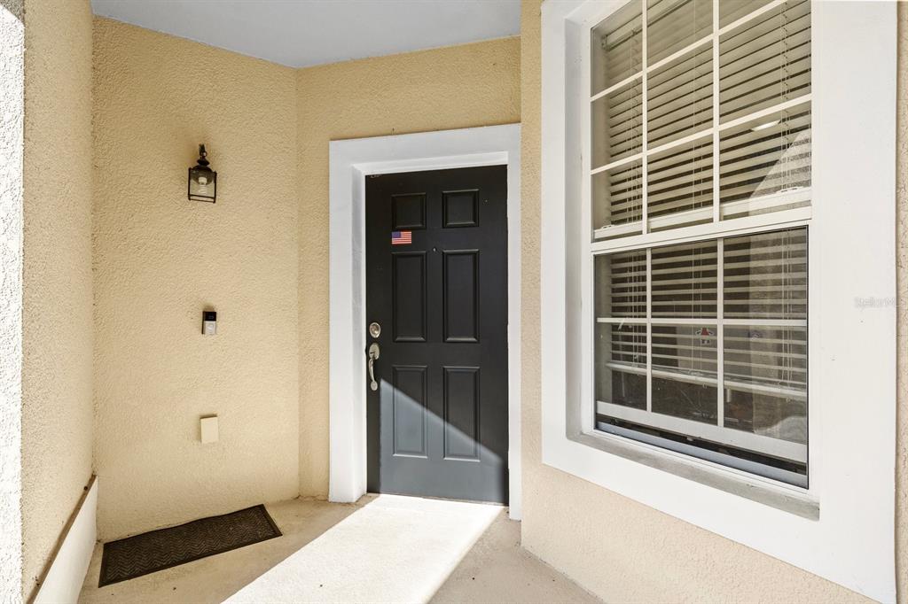 A front entryway features a black door, a window with blinds, and a wall-mounted light — 409 HILGARD COVE UNIT 106, SANFORD, FL