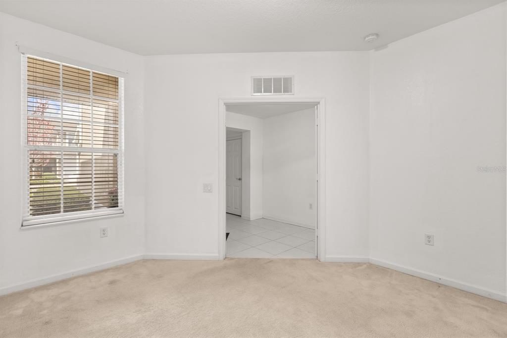 A carpeted room with a window and a doorway leading to a tiled area — 409 HILGARD COVE UNIT 106, SANFORD, FL