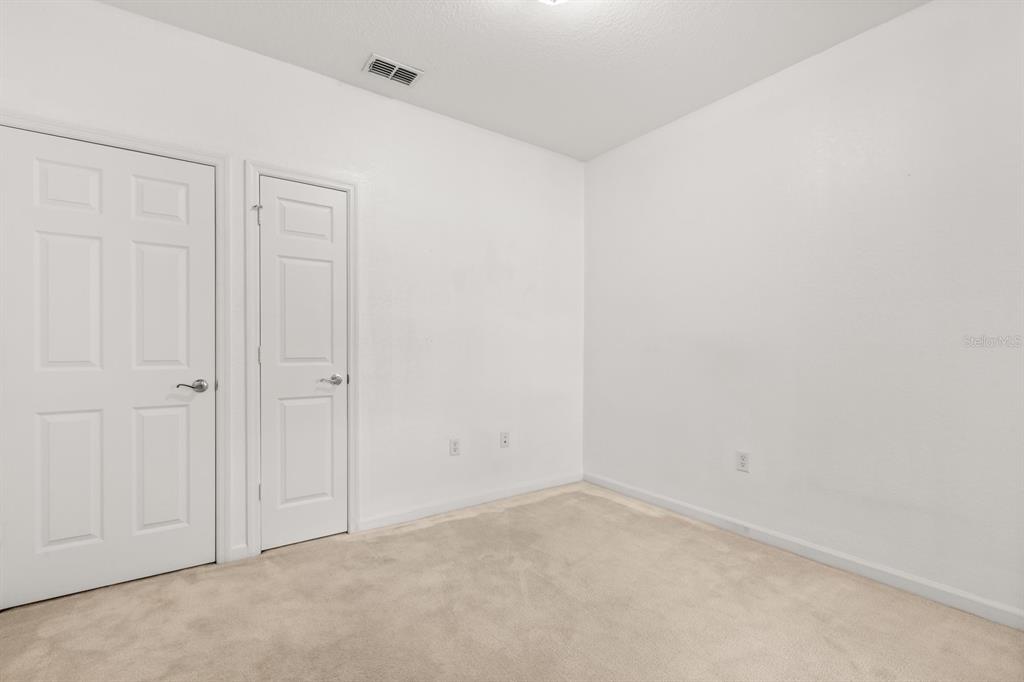 An empty room features white walls, beige carpeting, and two white interior doors — 409 HILGARD COVE UNIT 106, SANFORD, FL