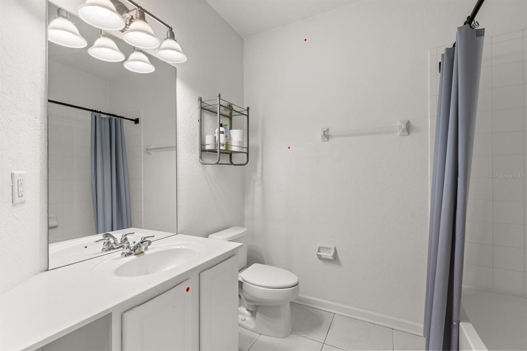 A bathroom features a white vanity, a large mirror, a toilet, and a shower curtain — 409 HILGARD COVE UNIT 106, SANFORD, FL