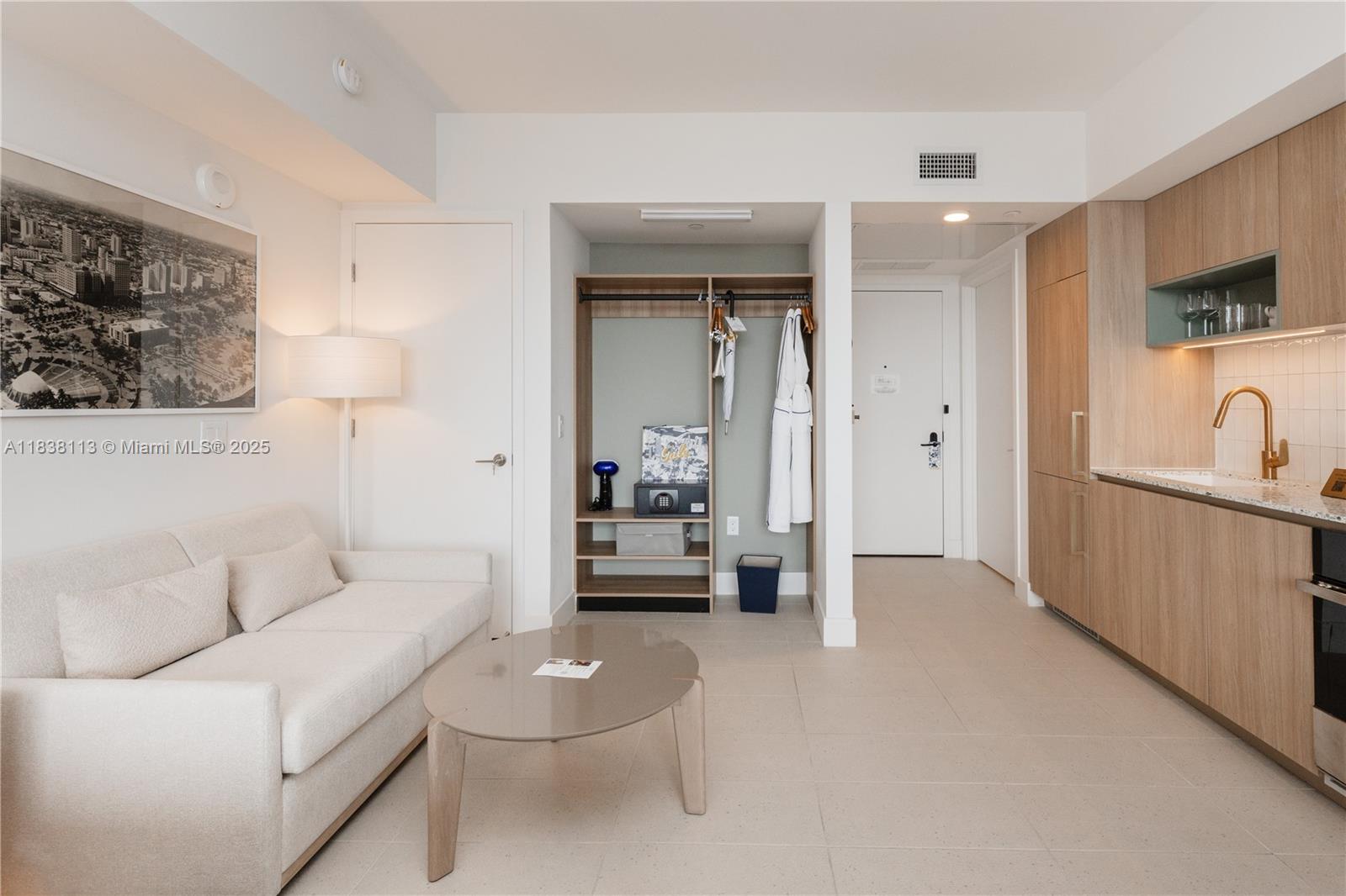 This studio apartment features a sofa, a kitchenette with wood cabinetry, and an open closet — 601 NE 1st ave # 3612, Miami FL 33132, MIAMI, FL