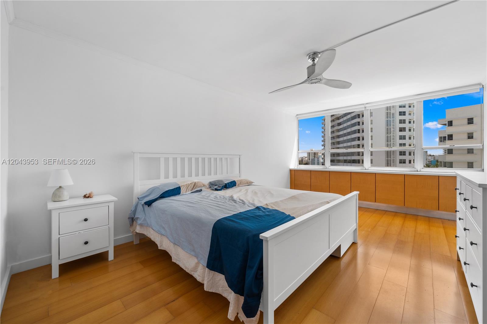 A bedroom features a white bed frame, light wood flooring, and a large window view — 11 Island Ave # 610, Miami Beach FL 33139, MIAMI BEACH, FL
