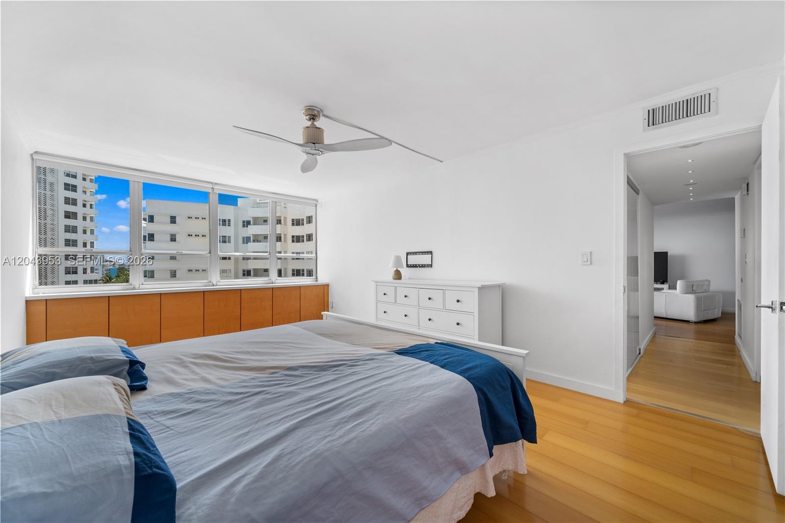 A bedroom features light wood flooring, a white dresser, a ceiling fan, and large windows — 11 Island Ave # 610, Miami Beach FL 33139, MIAMI BEACH, FL