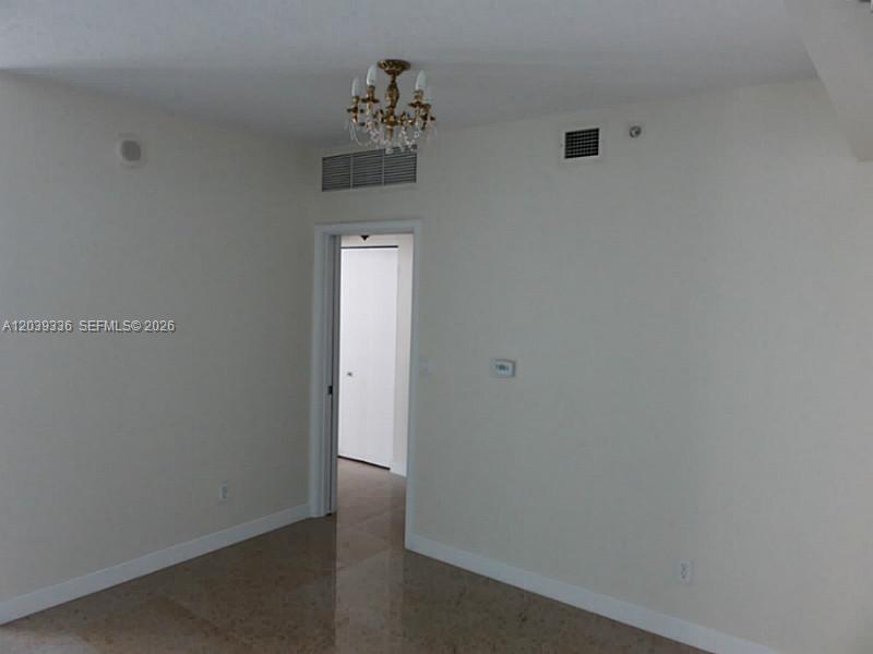 An interior room features light-colored walls, a chandelier, and polished tile flooring — 325 S BISCAYNE BLVD # 4122, Miami FL 33131, MIAMI, FL