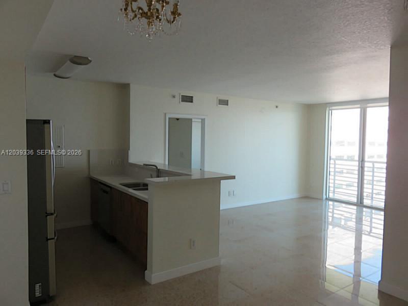An open-concept kitchen with a breakfast bar overlooks a living area with tile flooring — 325 S BISCAYNE BLVD # 4122, Miami FL 33131, MIAMI, FL