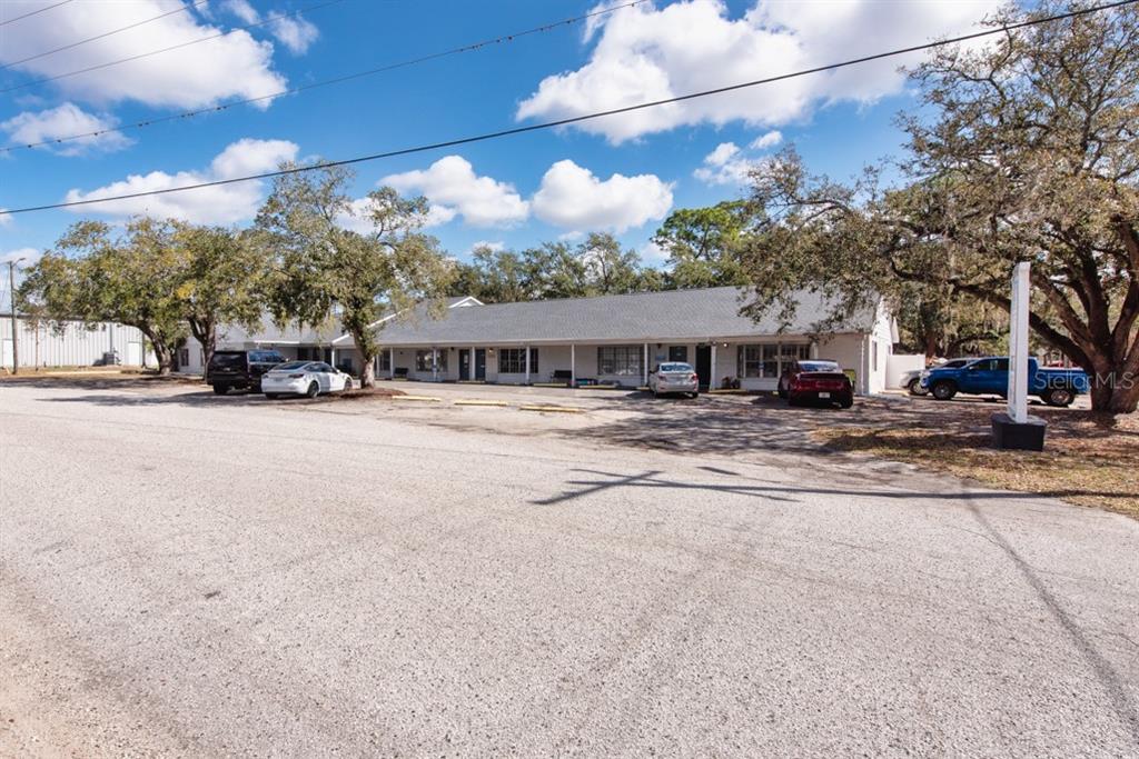 A single-story commercial building with a gray roof and parking lot under a blue sky — 7414 COMMERCE STREET UNIT 102, RIVERVIEW, FL
