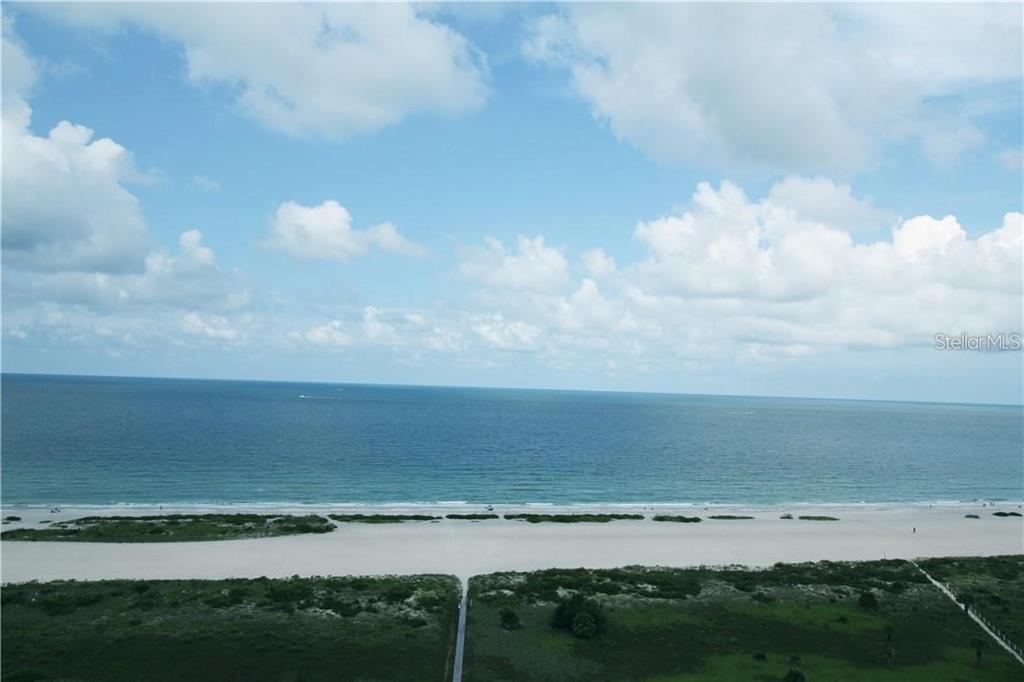 An aerial view shows a sandy beach, ocean, and blue sky with scattered clouds — 1230 GULF BOULEVARD UNIT 1805, CLEARWATER, FL