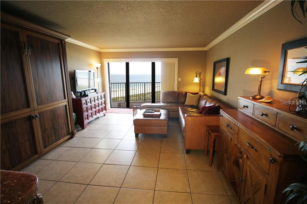 A living room with tile floors, a leather sectional, and a balcony overlooking the ocean — 1230 GULF BOULEVARD UNIT 1805, CLEARWATER, FL