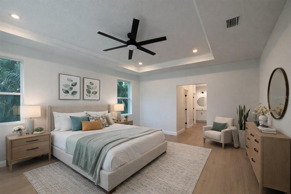 A modern bedroom features a king bed, a ceiling fan, and a light wood dresser — 131 KINGS DRIVE, ROTONDA WEST, FL