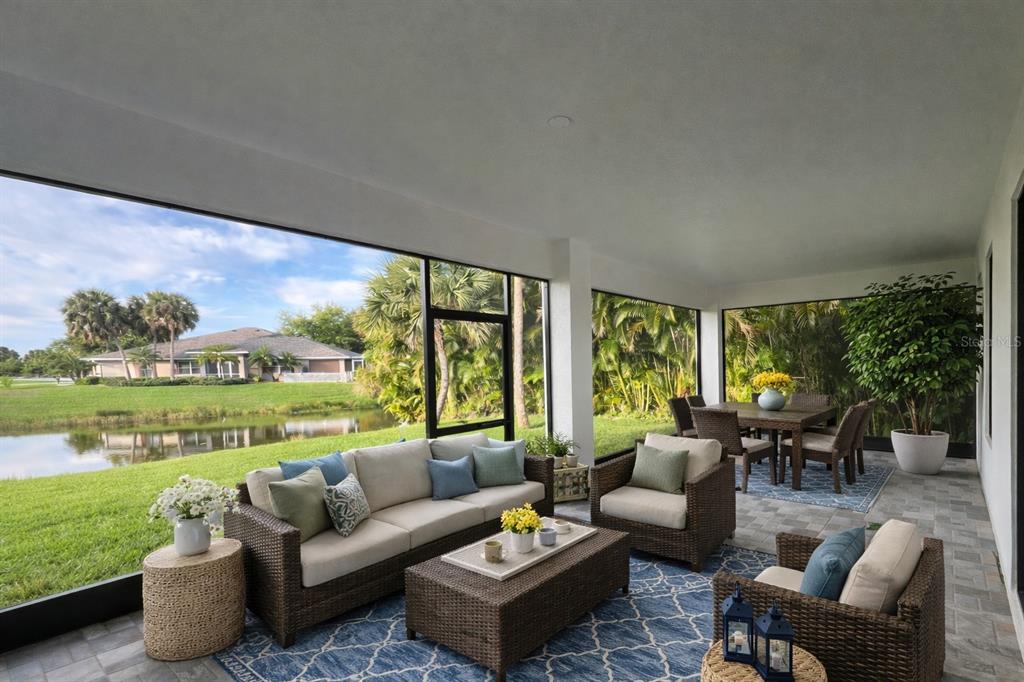 A screened-in patio features wicker furniture, a blue patterned rug, and views of a pond — 131 KINGS DRIVE, ROTONDA WEST, FL