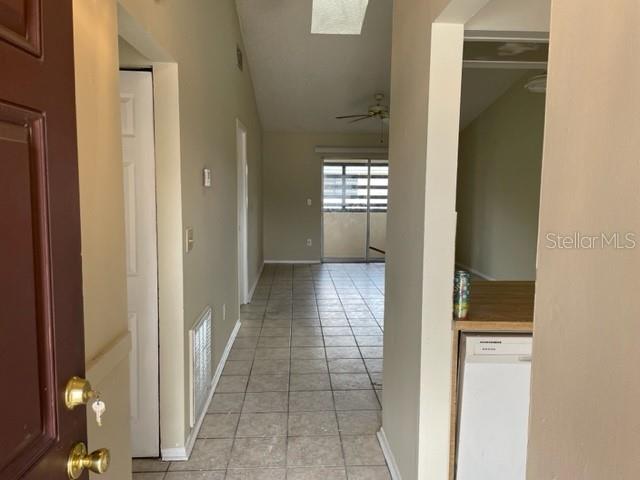 A view from an entryway looking down a tiled hallway toward a sliding glass door — 4721 ALMOND WILLOW DRIVE, ORLANDO, FL