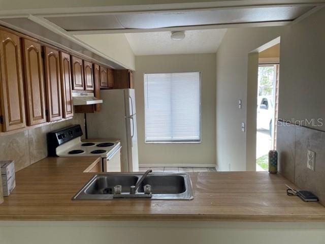 A kitchen features wood cabinets, a laminate countertop, a double sink, and a white refrigerator — 4721 ALMOND WILLOW DRIVE, ORLANDO, FL