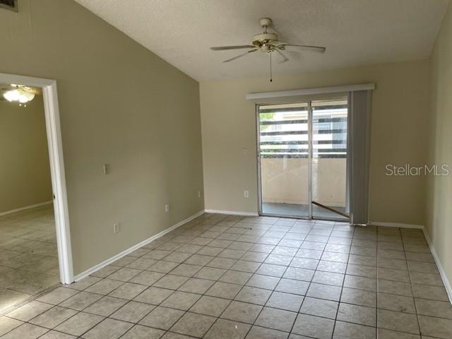 An interior view of a room with light-colored tile flooring, a ceiling fan, and sliding doors — 4721 ALMOND WILLOW DRIVE, ORLANDO, FL