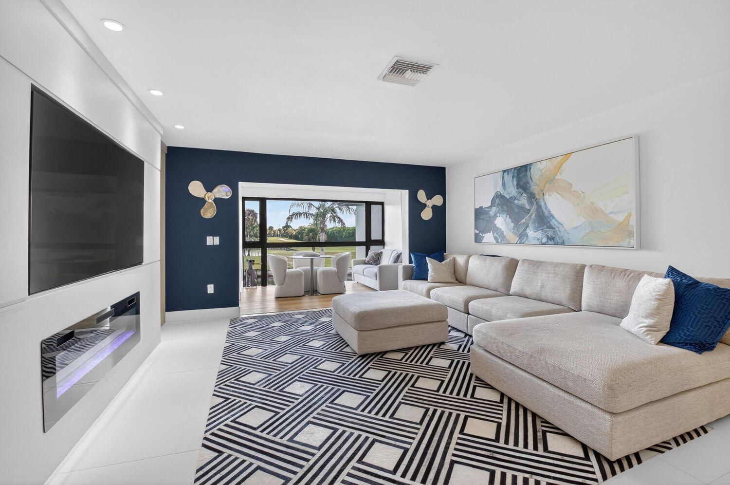 A modern living room features a large sectional sofa, patterned rug, fireplace, and dark accent wall — 23 Southport Lane # D, Boynton Beach FL 33436, BOYNTON BEACH, FL