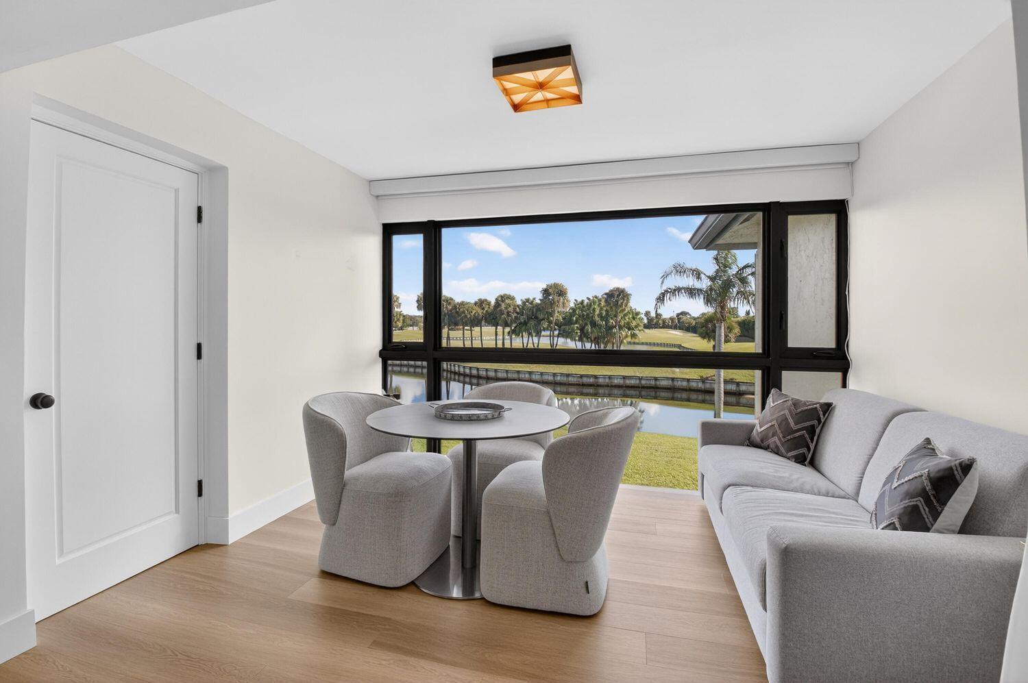 A room with a dining set and sofa overlooks a lake and golf course — 23 Southport Lane # D, Boynton Beach FL 33436, BOYNTON BEACH, FL