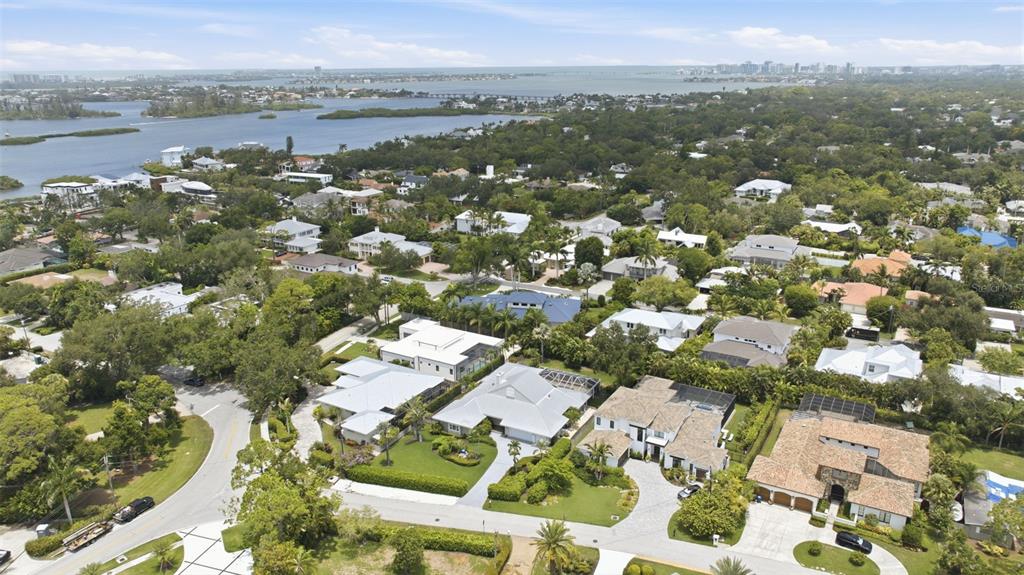 An aerial view shows a residential neighborhood with houses, lush trees, and a nearby bay — 1511 N LAKE SHORE DRIVE, SARASOTA, FL