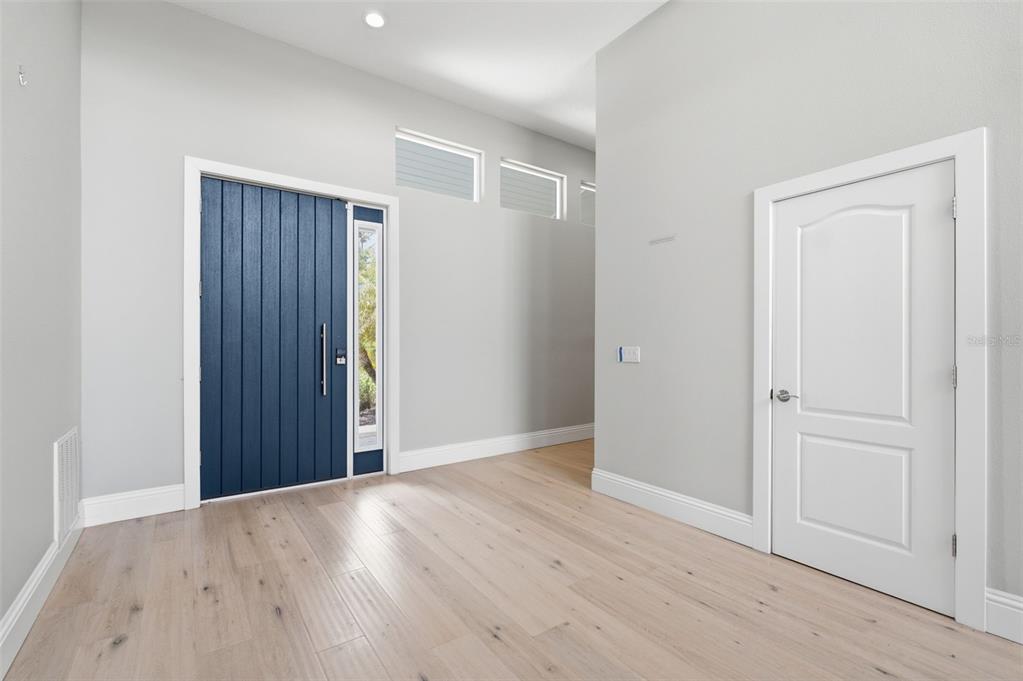 An entryway features light wood flooring, a blue front door, and a white interior door — 1511 N LAKE SHORE DRIVE, SARASOTA, FL
