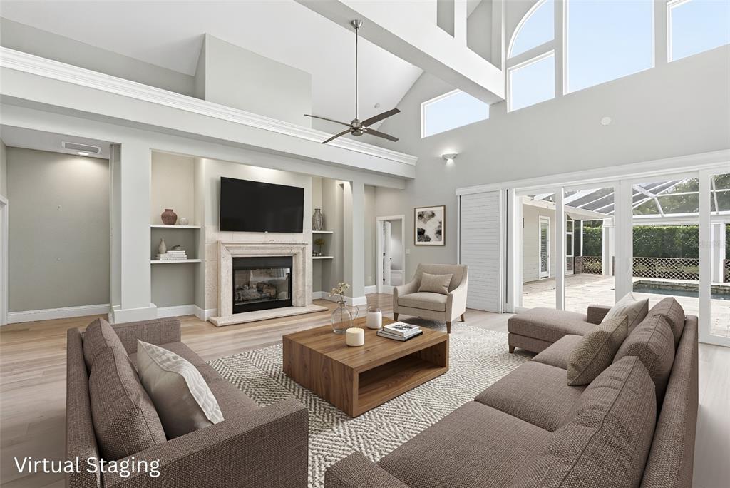 A living room with a fireplace, vaulted ceilings, and large windows overlooking a pool area — 1511 N LAKE SHORE DRIVE, SARASOTA, FL