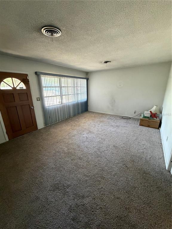 A living room features beige carpet, a large window with vertical blinds, and a wooden door — 4506 NE 11TH STREET, OCALA, FL