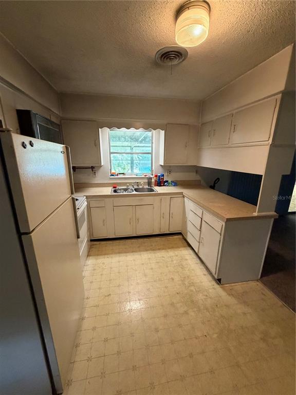 A kitchen features white cabinets, a laminate countertop, a window above the sink, and linoleum flooring — 4506 NE 11TH STREET, OCALA, FL