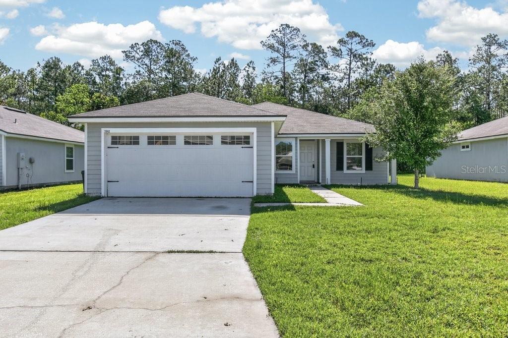 A single-story house with gray siding, a two-car garage, and a concrete driveway — 7082 PLYMOUTH GROVE COURT, JACKSONVILLE, FL